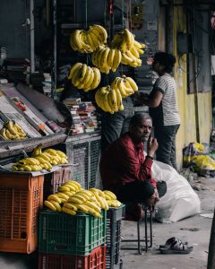 A man sits outside a smalls shop (micro-enterprise) that sells knick-knacks